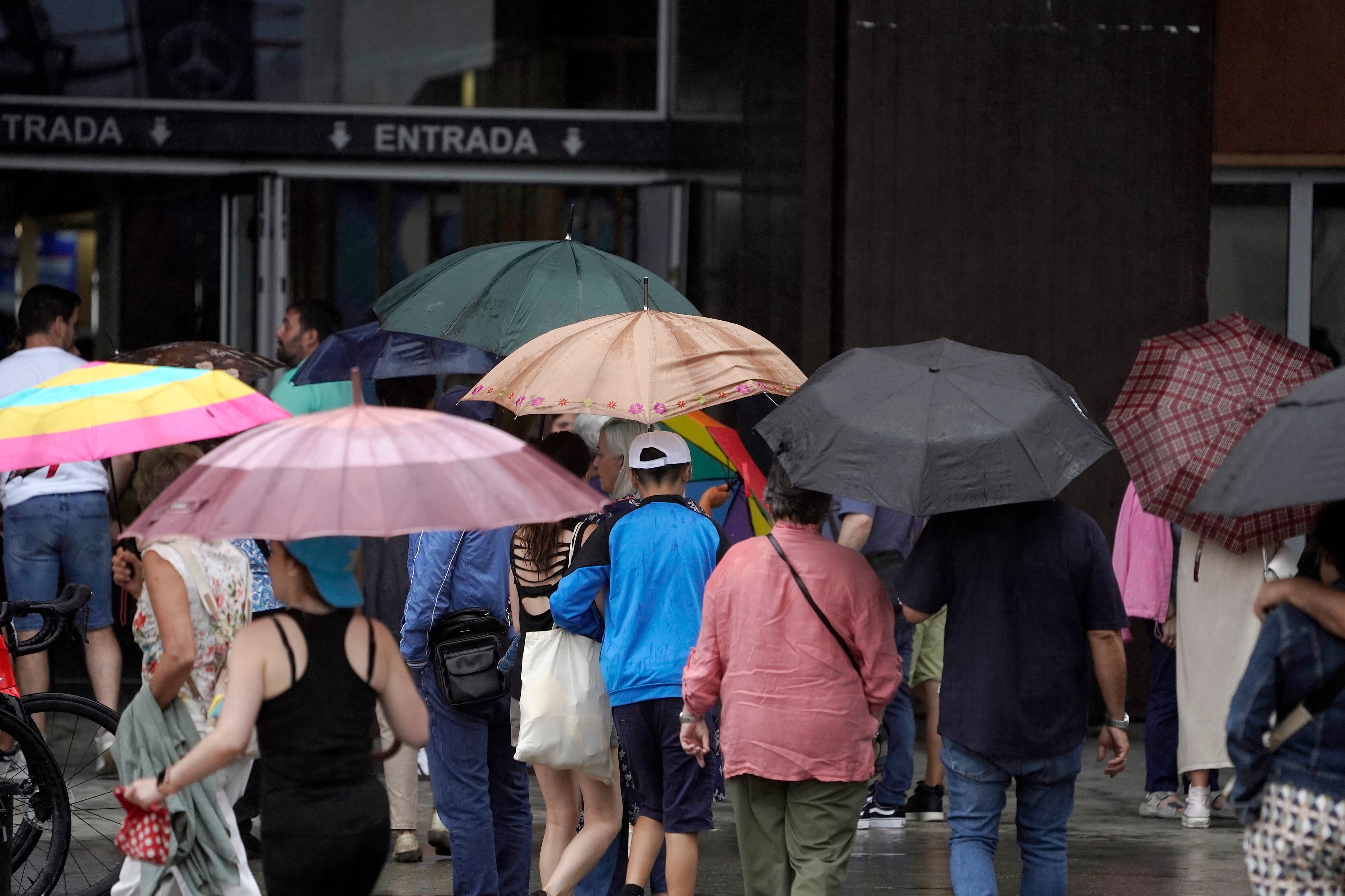 Personas protegiéndose de la lluvia durante la pasada DANA este mes de agosto en Gijón.