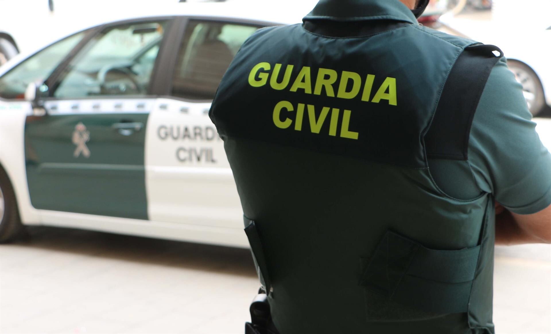 Archivo - Agente de la Guardia Civil junto a un vehículo del instituto armado- GUARDIA CIVIL - Archivo