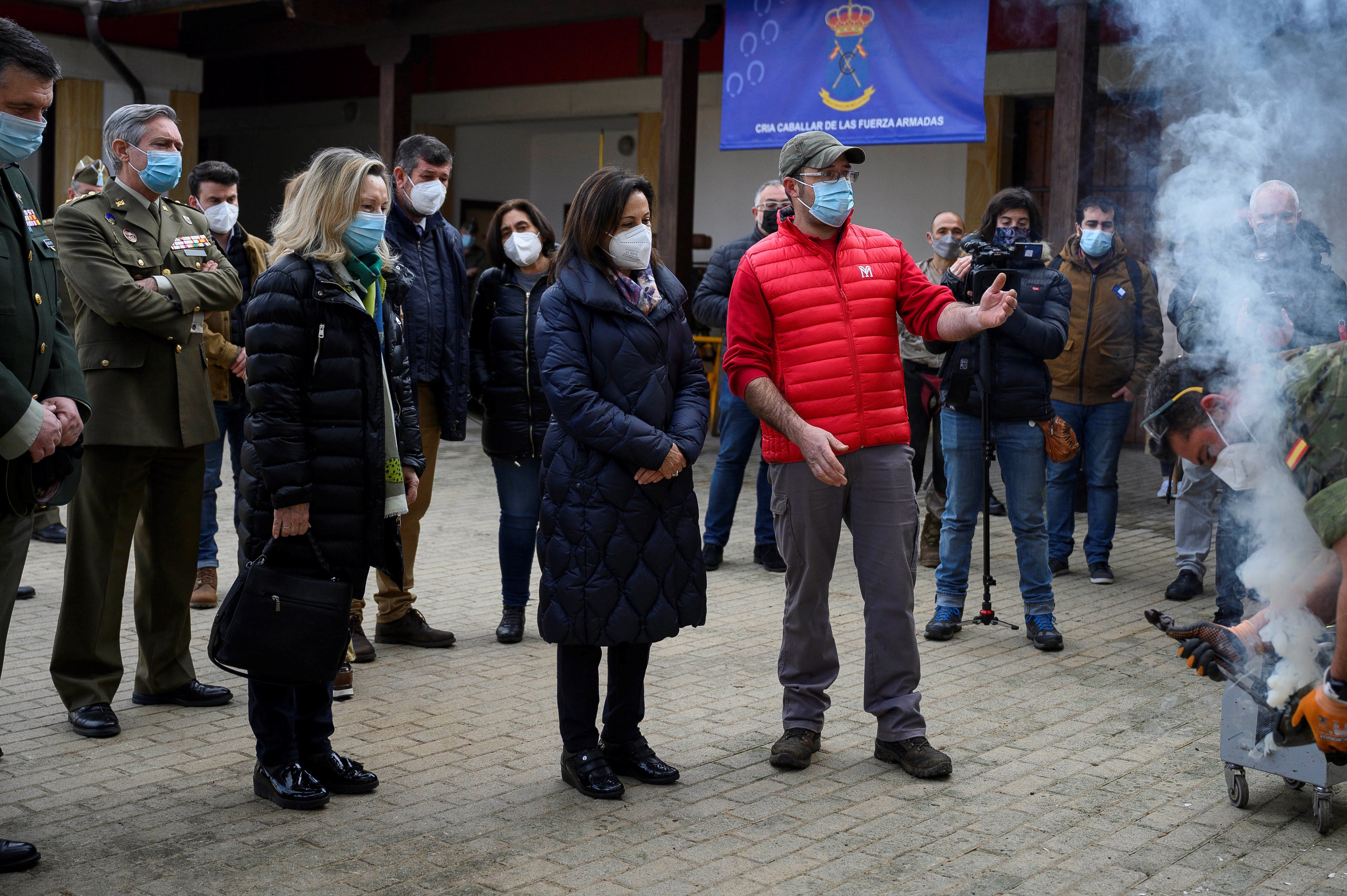 La ministra de Defensa, Margarita Robles, observa como colocan herraduras a un caballo, durante su visita este jueves al centro militar de cria caballar en la localidad cántabra de Ibio.