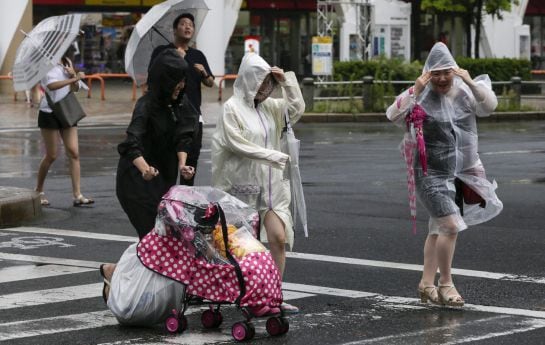 Tres mujeres se protegen de la lluvia y el fuerte viento provocado por el tifón Mindulle en Tokio.