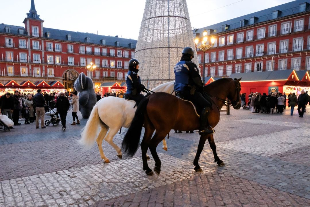 Dos agentes de la Policía Nacional a caballo, patrullan por la Plaza Mayor de Madrid.