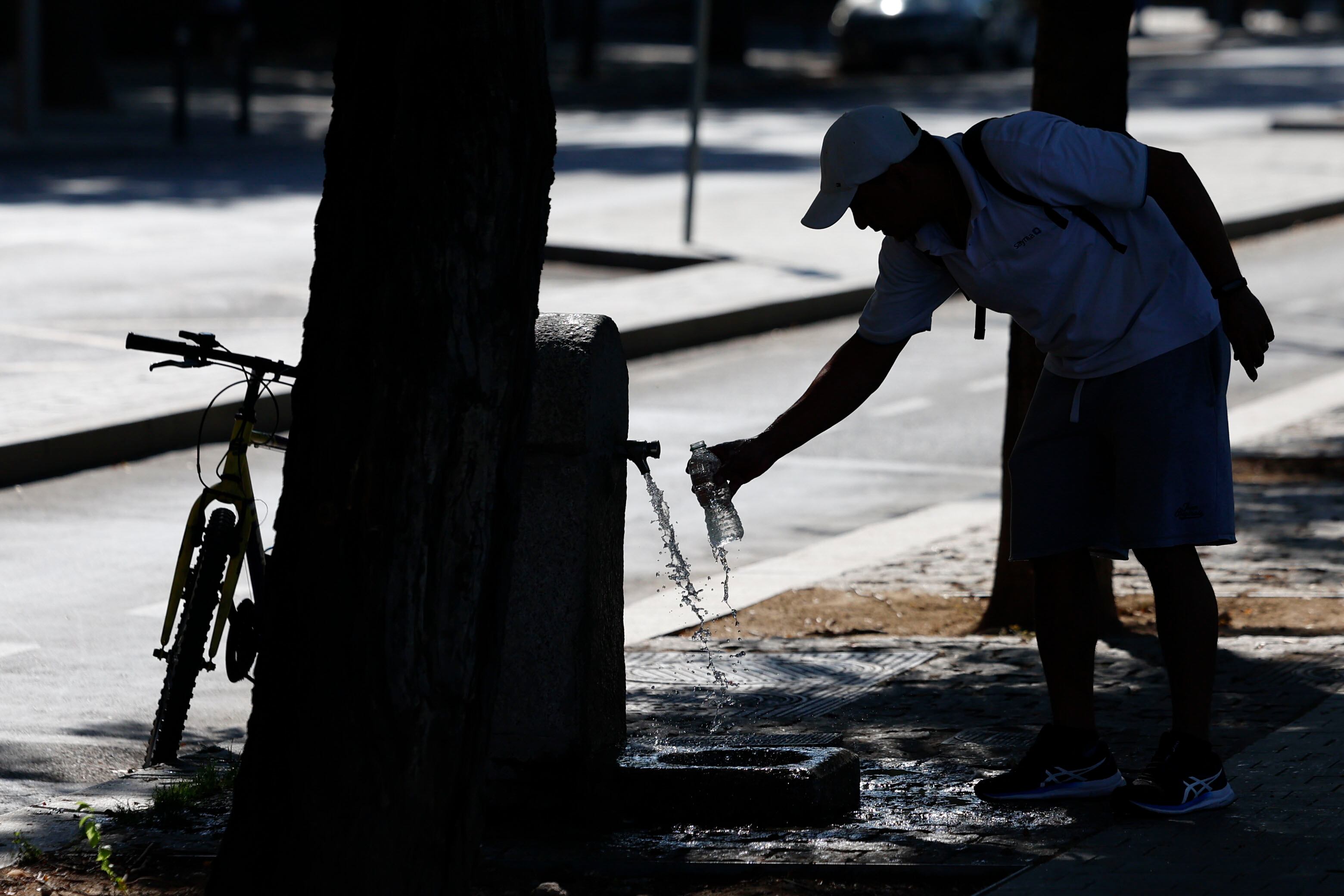 Imagen de archivo de un hombre rellenando una botella de agua en una fuente pública. EFE/ Mariscal