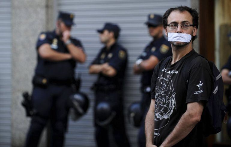 Un hombre con la boca tapada y rodeado de policía durante una manifestación contra la &#039;Ley Mordaza&#039; en Gijón. 