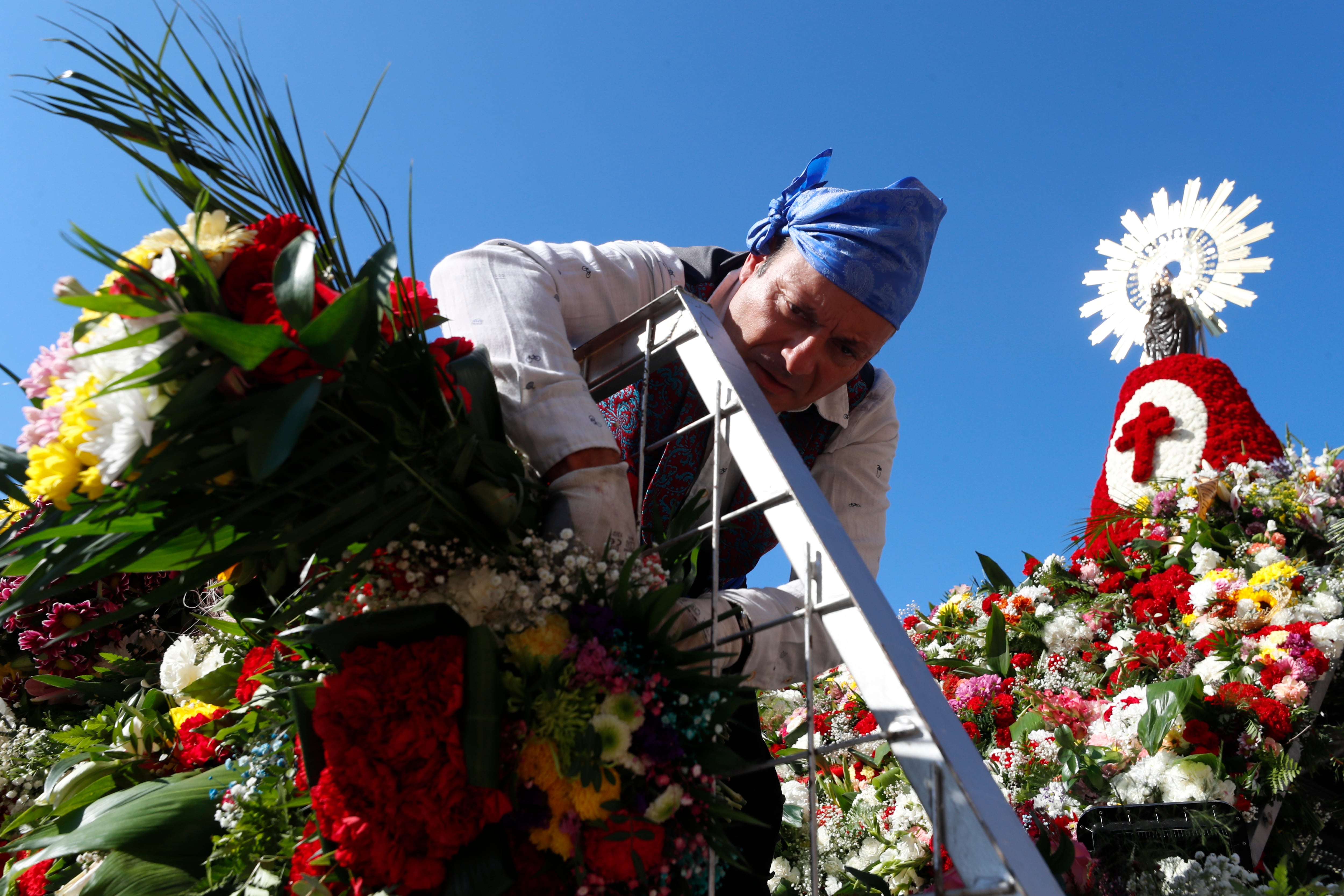 ZARAGOZA, 12/10/2022.- Un hombre coloca flores a la imagen de la Virgen del Pilar, en una estructura levantada en el centro de la plaza de Zaragoza que lleva su nombre, una ofrenda llena de ilusión que se espera de récord tras dos años de pandemia, con más grupos inscritos que en 2019 y la previsión de alcanzar alrededor de siete millones de flores. EFE/ Javier Cebollada
