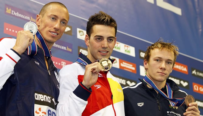 El nadador español Rafael Muñoz Pérez junto al francés Frederick Bousquet y el bielorruso Yauhen Tsurkin posan con su medallas en el podio tras disputar la final masculina de los 50 metros mariposa, durante el Campeonato europeo de natación que se celebra