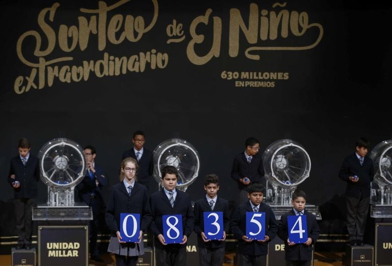 Los encargados de mostras las tablas en el Sorteo del Niño muestran el número agraciado con el primer premio.