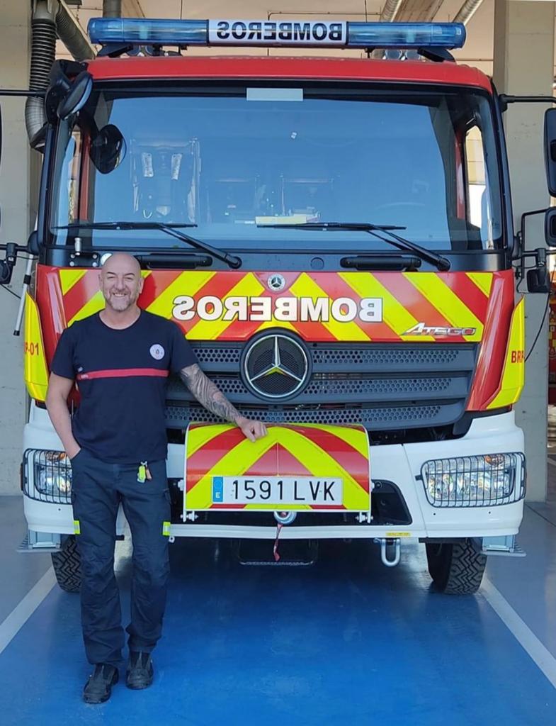 El bombero Manuel Cortés delante de un vehículo.