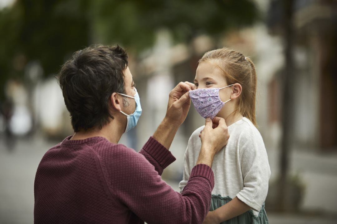 Padre poniendo mascarilla a su hija