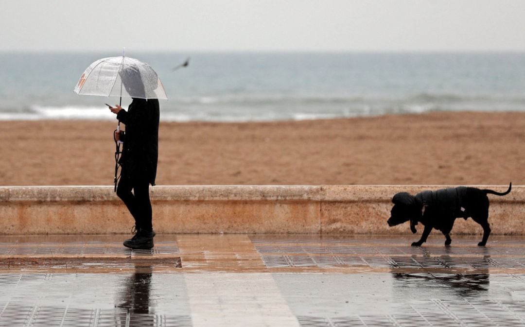 Una persona pasea bajo la lluvia cuando la borrasca Gloria, que trae este domingo un temporal de lluvia, nieve, viento y olas