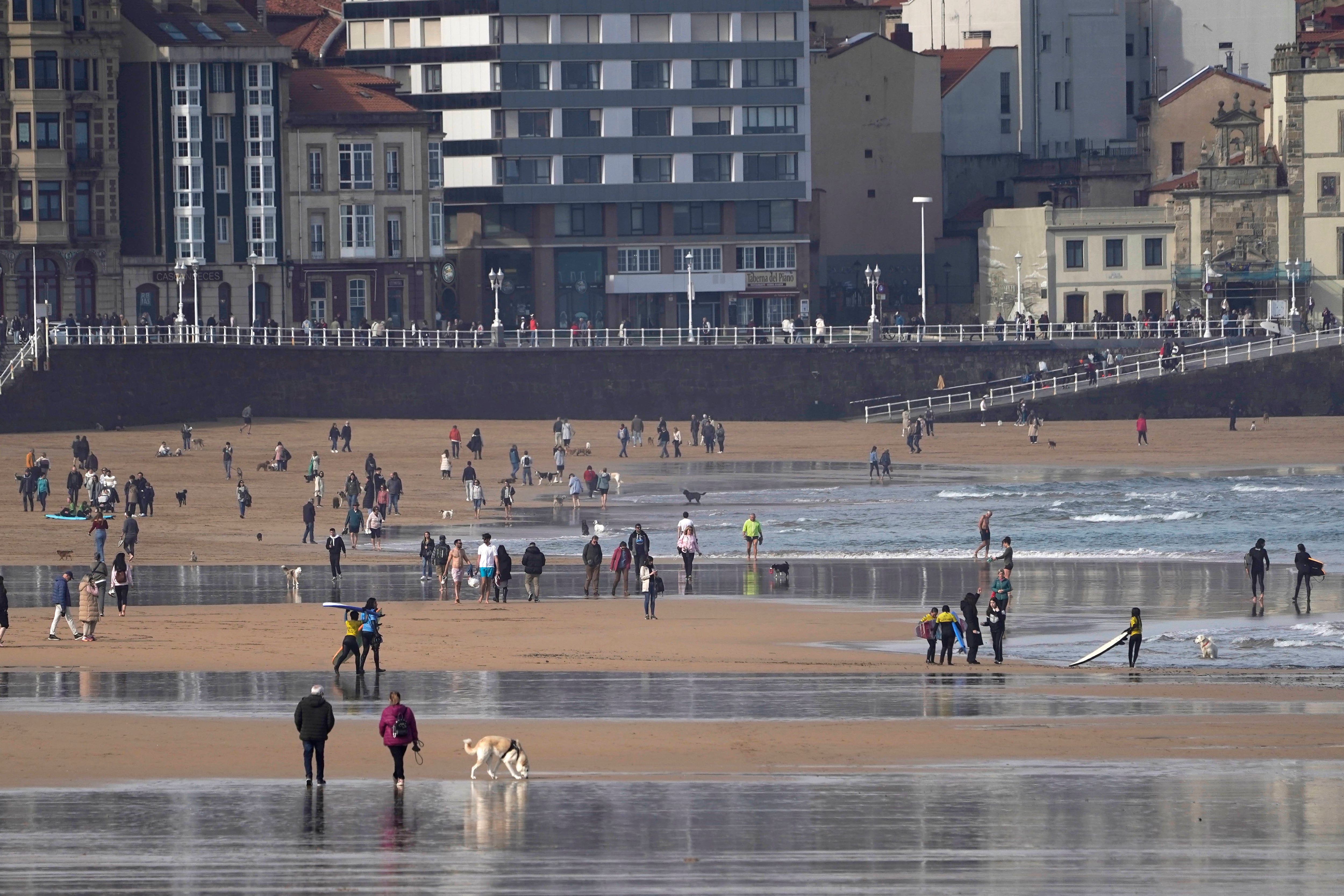 Surfistas y paseantes en la playa de San Lorenzo esta mañana