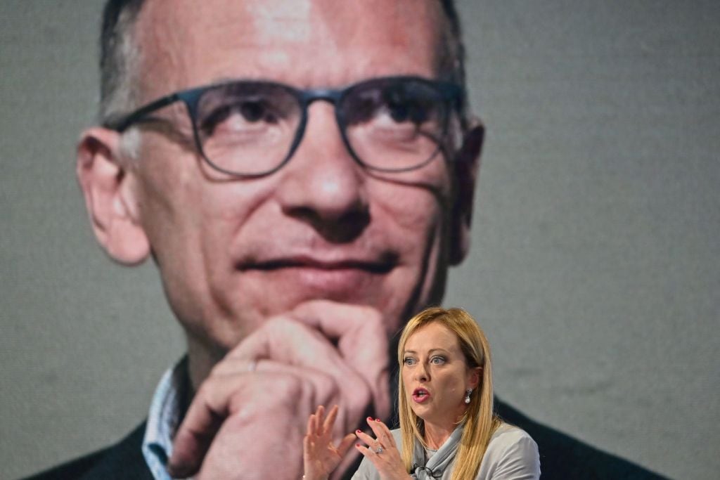 Giorgia Meloni habla frente a una imagen de su principal contendiente, Enrico Letta.