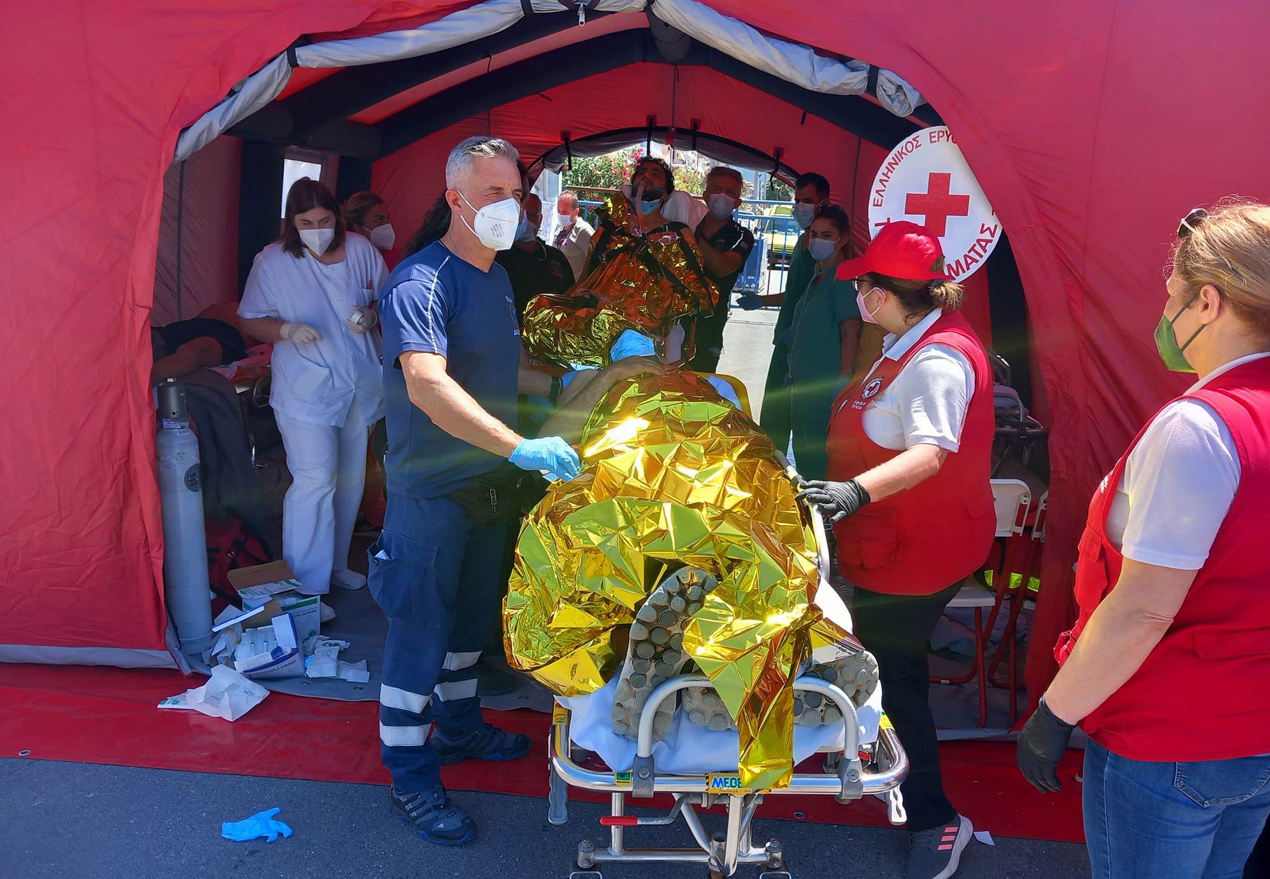 Paramédicos del Servicio Nacional de Ambulancias de Emergencia de Grecia (EKAV) y miembros de la Cruz Roja griega ayudan a migrantes supervivientes del hundimiento de un pesquero en su llegada en el puerto de Kalamata este miércoles. EFE/Bougiotis Evangelos