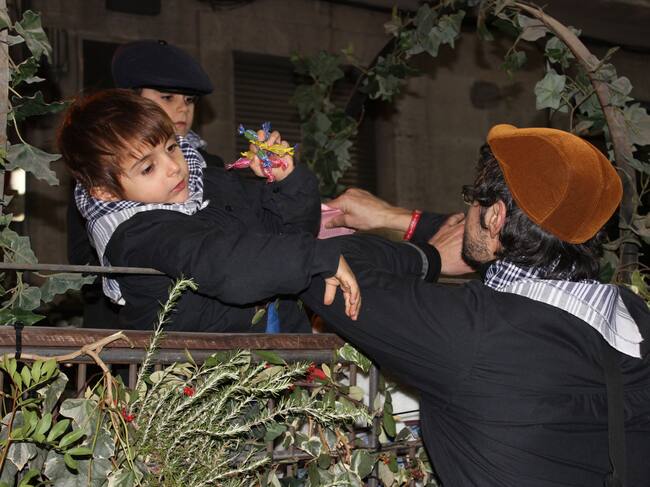 Un dels xicotets pastorets en un dels carros tirant caramels al públic