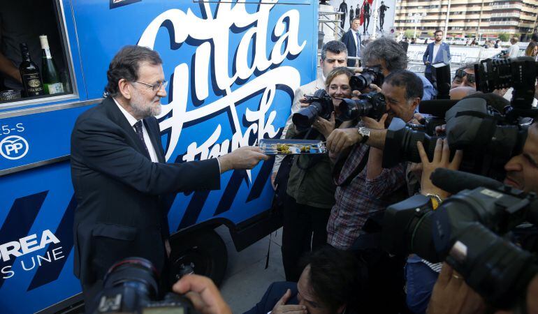 El presidente del Gobierno en funciones, Mariano Rajoy (i), ofrece pintxos en el &quot;Gilda Truck&quot;, durante un paseo hoy por las calles de San Sebastián dentro de la campaña para las elecciones autonómicas del 25 de septiembre.