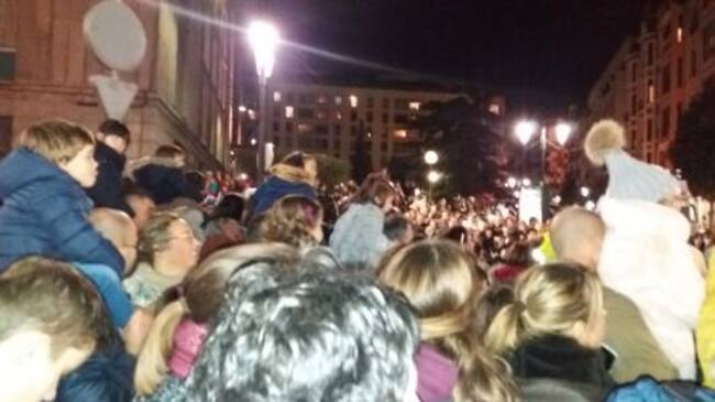 Niños a hombros de sus padres en una cabalgata abarrotada de gente.