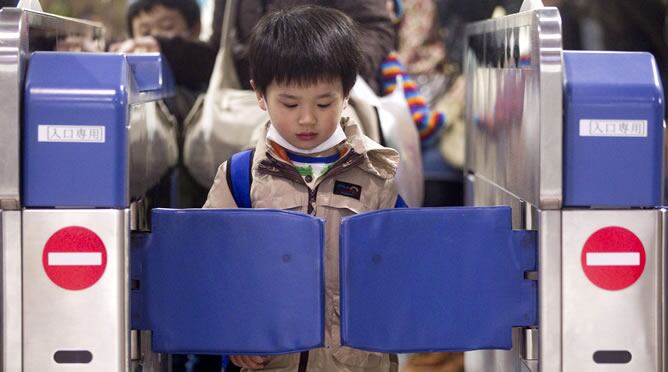 Un niño espera a que se abra el torno de acceso a una estación de Tokio (Japón)