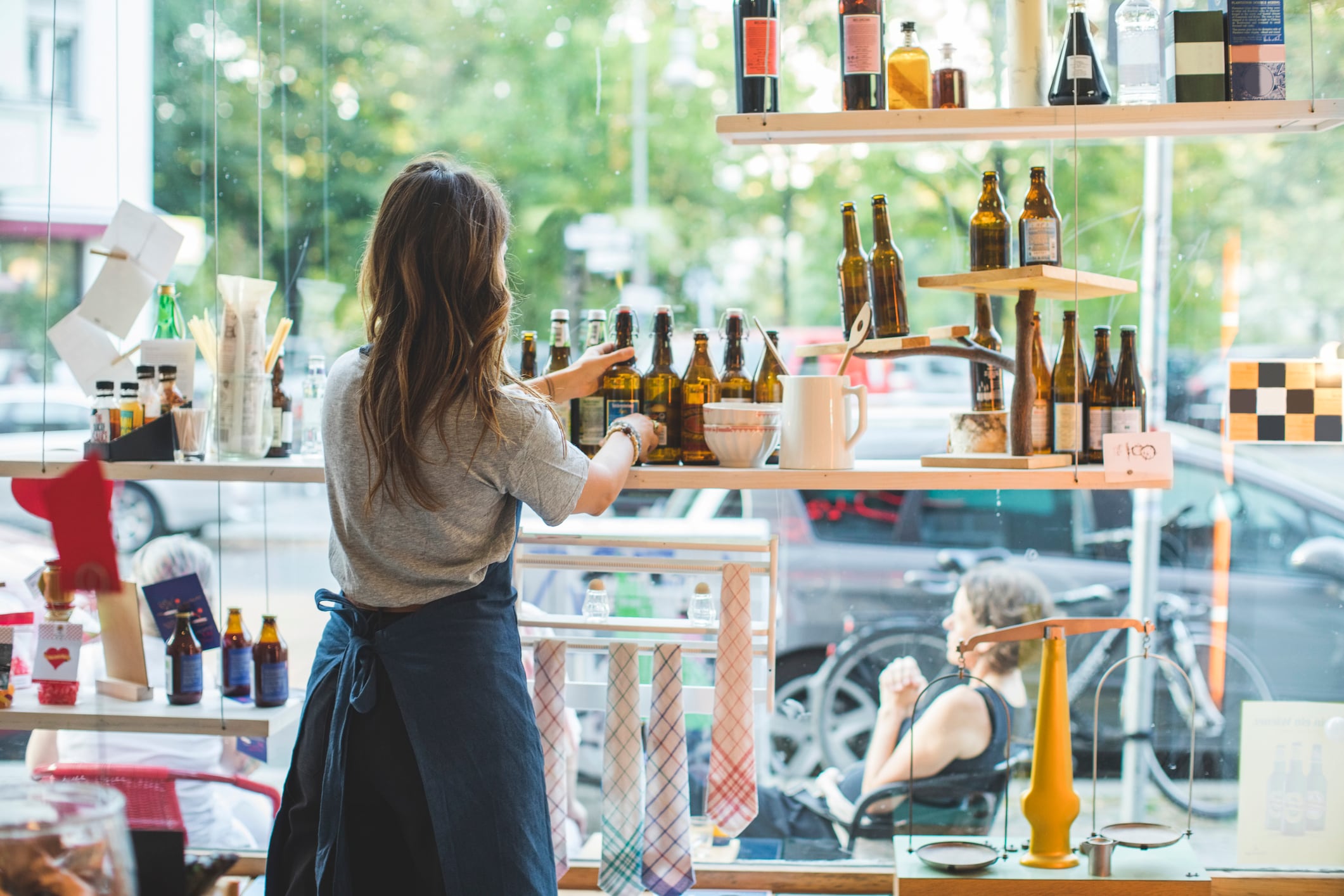 Una dependienta coloca botellas en el escaparate de una tienda