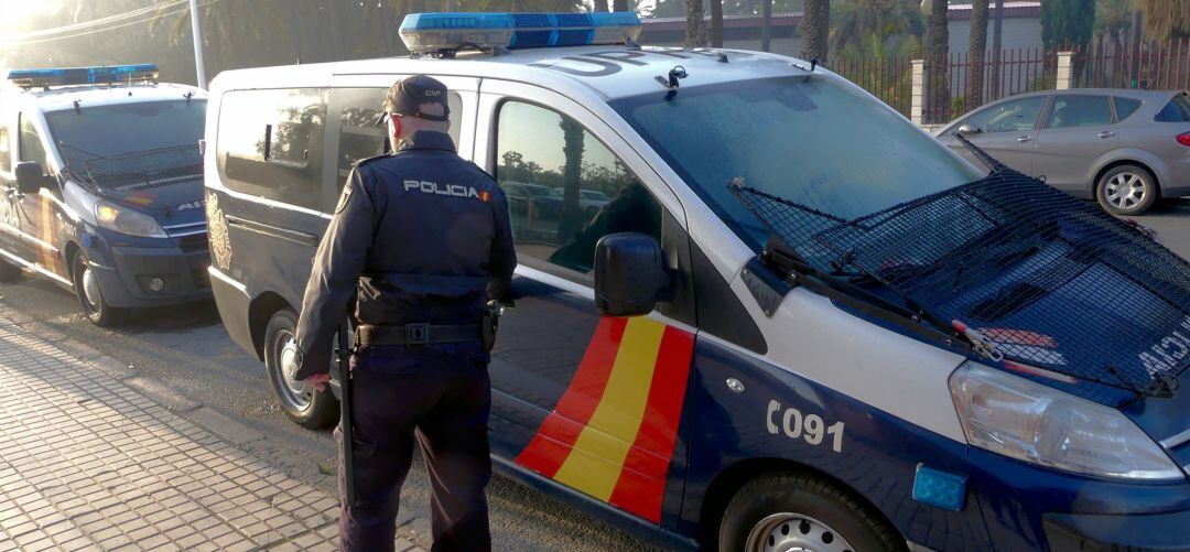 Un agente de la Policía Nacional junto a su coche patrulla