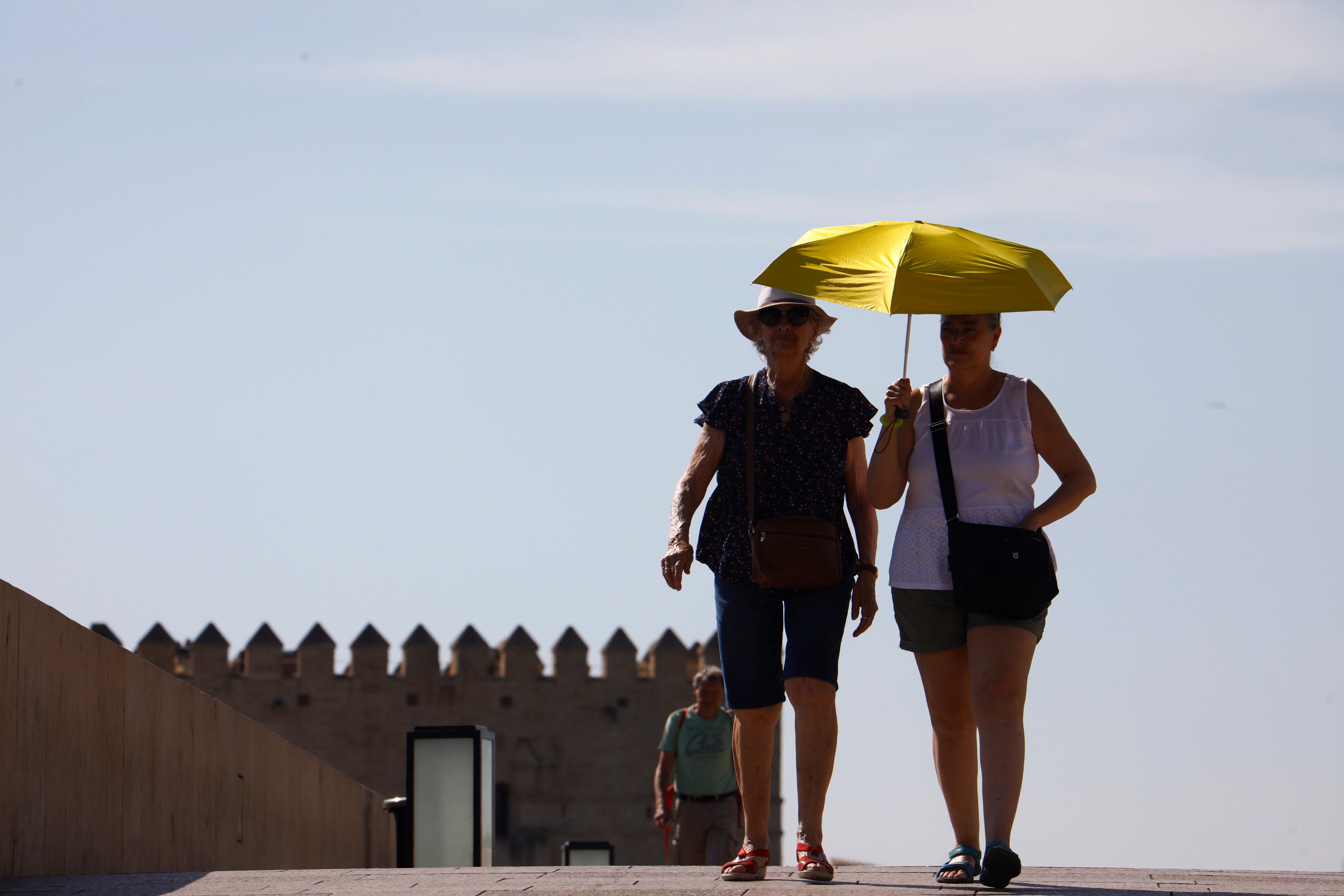 GRAFAND1495. CÓRDOBA, 12/07/2022.- Unos turistas se protegen del sol con un paraguas mientras pasean por los alrededores del Puente Romano de Córdoba, hoy cuando los termómetros superan los 42 grados en puntos de Andalucía como Córdoba y Sevilla y continúan en ascenso. EFE/Salas
