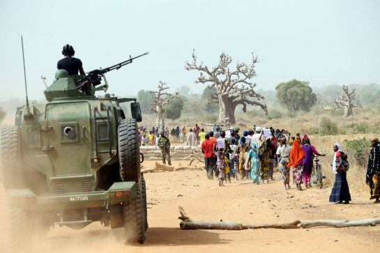 A Nigerian army armoured car gives cover to Chibok women as they walk along a road in Chibok, northeastern Nigeria, on March 5, 2015. Nigeria&#039;s government said that work had begun to rebuild a school in the northeastern town of Chibok from where Boko Hara