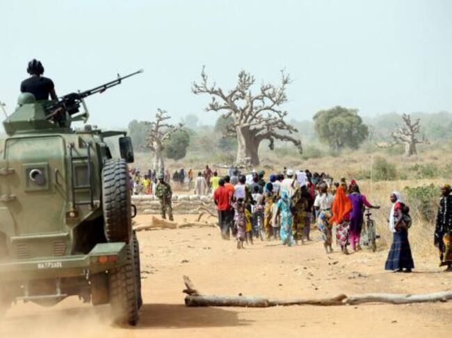 A Nigerian army armoured car gives cover to Chibok women as they walk along a road in Chibok, northeastern Nigeria, on March 5, 2015. Nigeria's government said that work had begun to rebuild a school in the northeastern town of Chibok from where Boko Hara