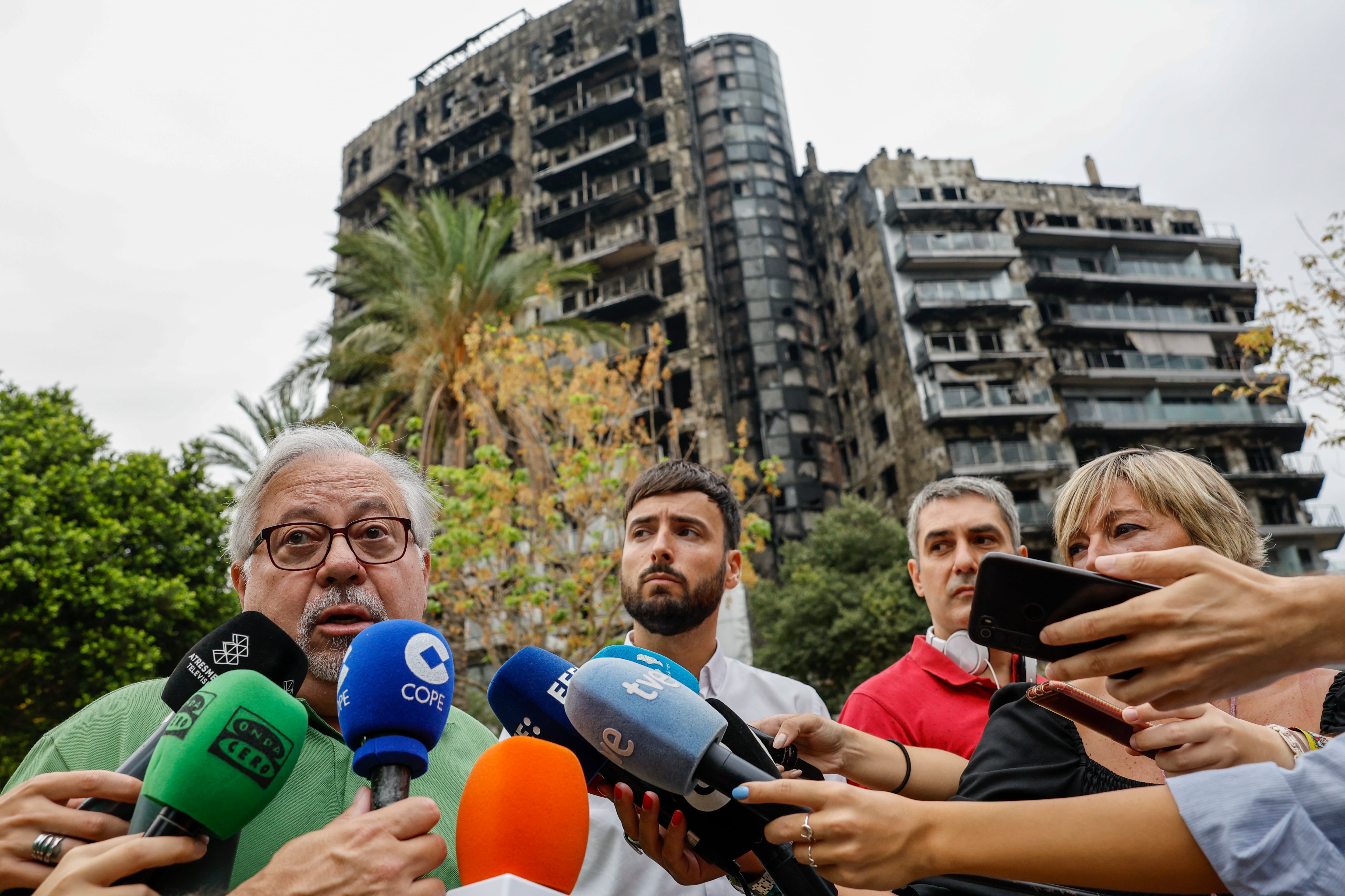 GRAFCVA2522. VALENCIA, 02/09/2024.- El presidente de APROICAM, Enrique Salvador (c), y el vicepresidente, Joé Mas (i), atienden a los medios de comunicación ante el edificio del barrio valenciano de Campanar cuyo incendio dejó diez víctimas mortales, y que pone en marchaeste lunes las labores de desescombro, en las que durante cuatro meses se retirarán pavimentos, alicatados, cubiertas, enseres y restos de la fachada ventilada, con un coste de 1,5 millones de euros. EFE/Biel Aliño
