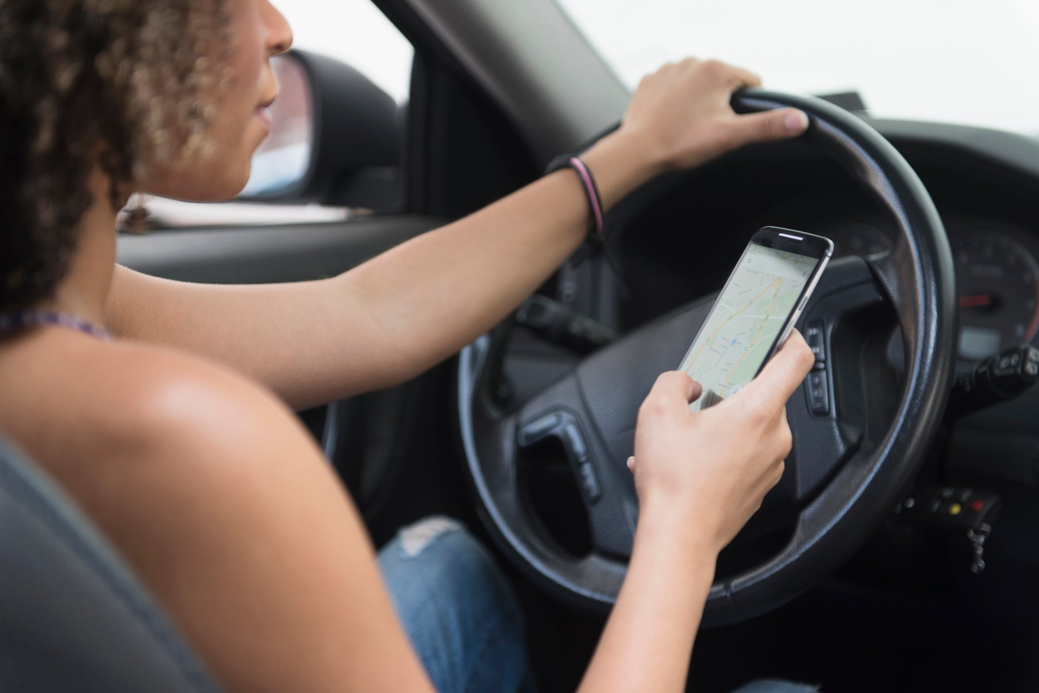 Una mujer utiliza el teléfono móvil en el coche.