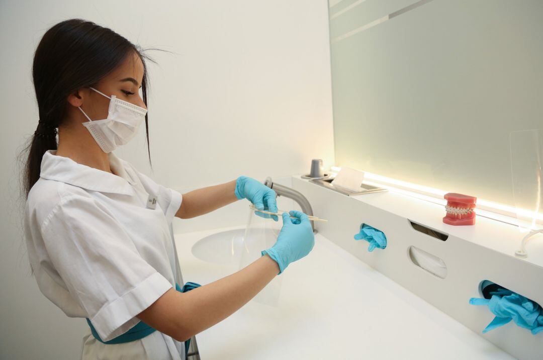 Una asistente dentista con mascarilla quirúrgica.