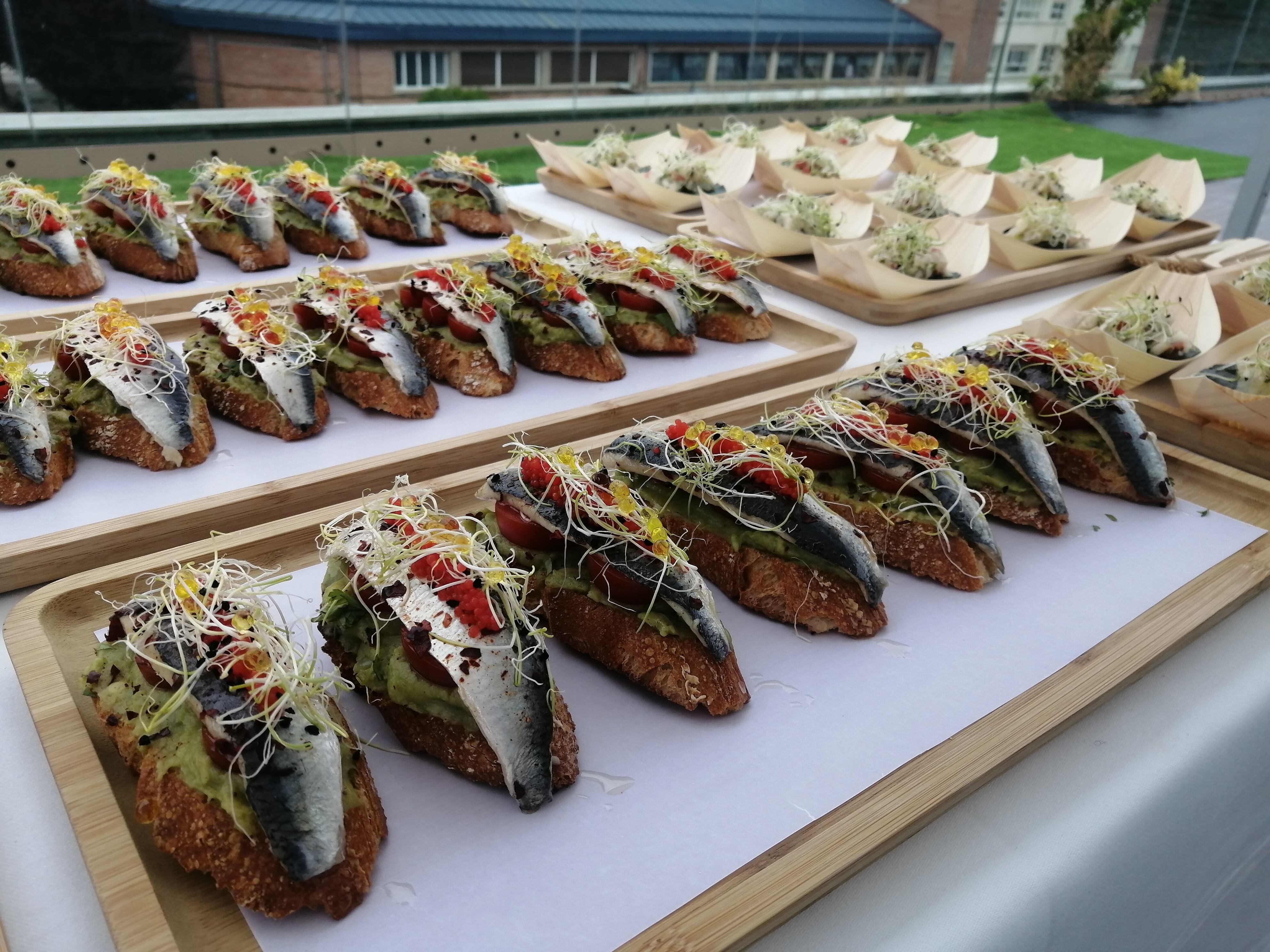 Tosta de guacamole y tomate cherry con filete de sardina encurtida, lascas de pimiento agridulce, perlas de alga roja, germinados de cebolla, cilantro, toque de lima y esferas de aceite de oliva