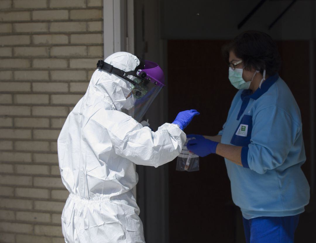 Un sanitario entrega las pruebas a otro, tras realizar una recogida de muestra desde el coche para detectar casos de coronavirus