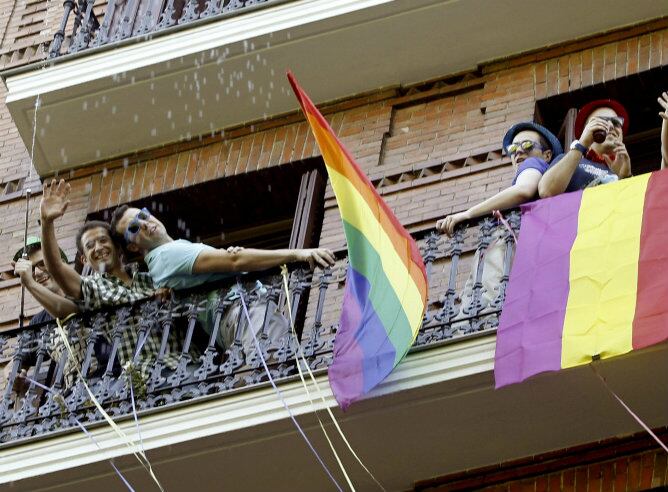 Varias personas exhiben en un balcón banderas del arcoíris con motivo de la manifestación del Orgullo Gay