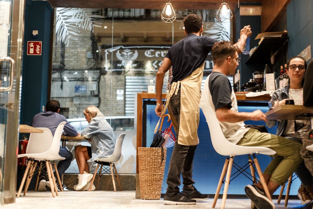 Un empleado de Street & Soul trabaja en las instalaciones de su restaurante con varios comensales, en Toledo, Castilla-La Mancha