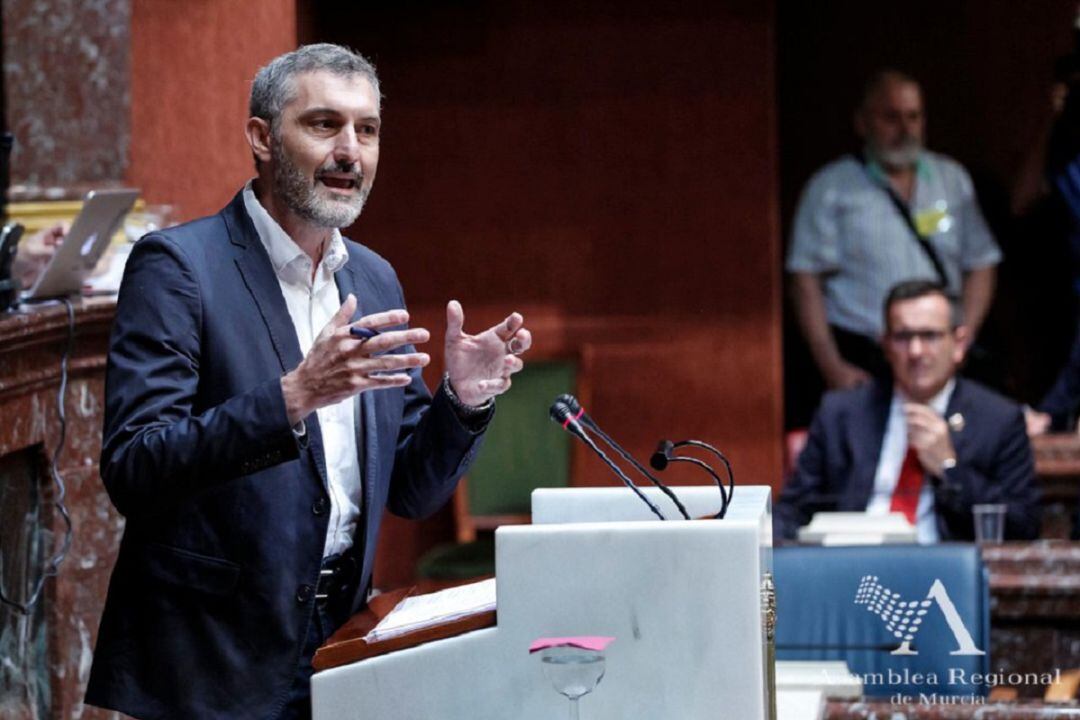 El diputado de Podemos, Óscar Urralburu, durante su intervención en el debate de investidura de López Miras. Al fondo, el portavoz del Grupo Socialista, Diego Conesa