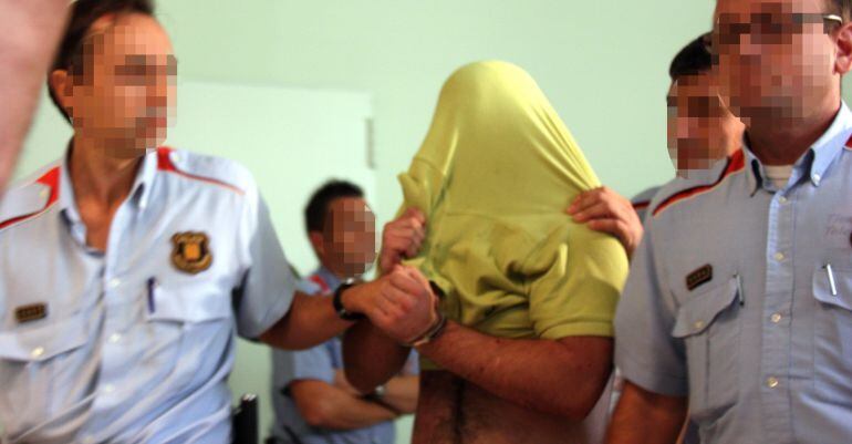 El jove, passant a disposició judicial, tapant-se amb la samarreta i custodiat per diversos Mossos. Arxiu 24 de març del 2015
