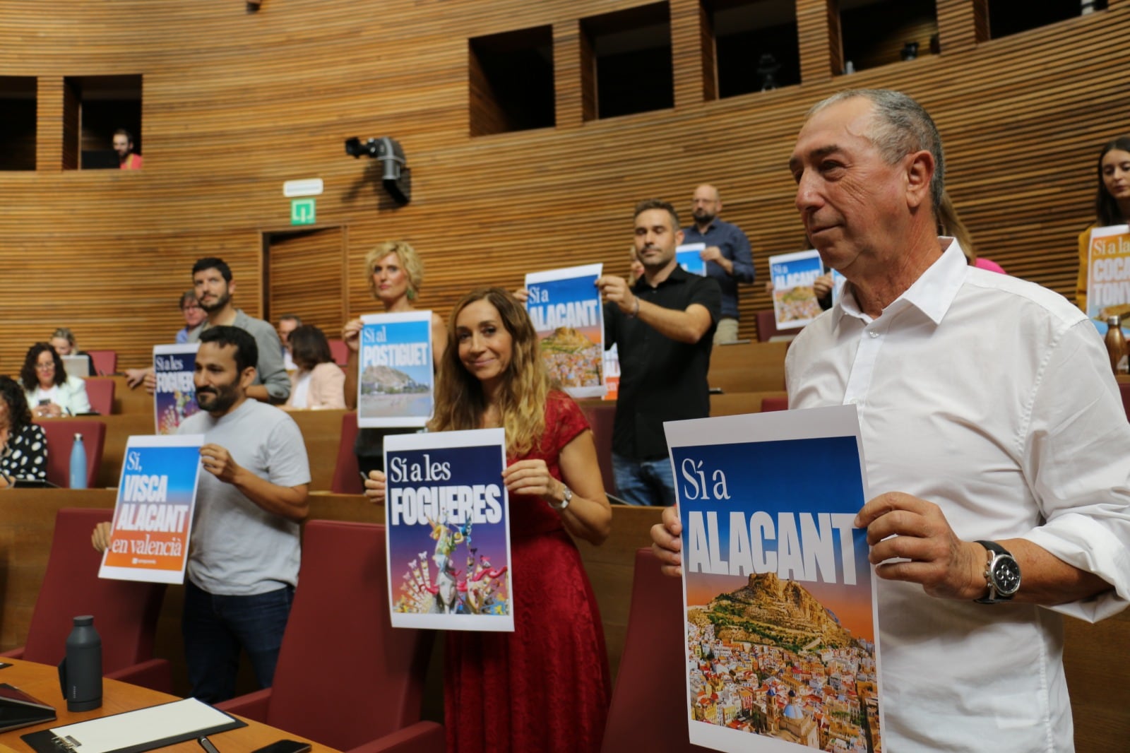 Diputados de Compromís con carteles contra el intento de Vox en el Ayuntamiento de Alicante de que sea reconocido municipio de predominio lingüístico castellano