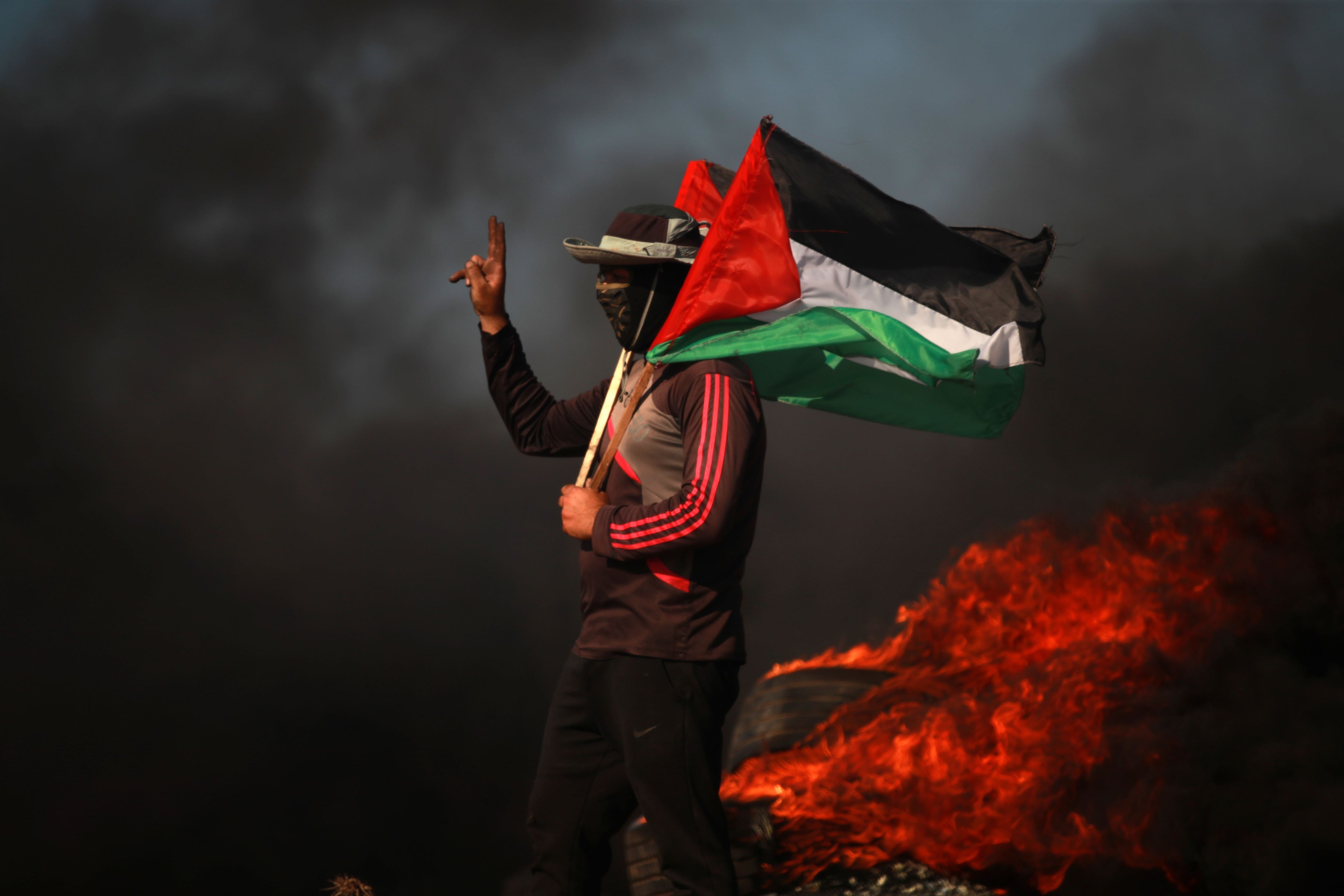 Un joven palestino con una bandera cerca de la  valla que separa Israel de Gaza