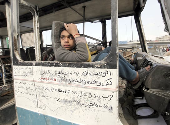 Un adolescente egipcio mira desde el interior de un microbus calcinado en la plaza Tahrir