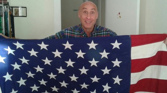 Steven Marcus posa desde su casa en Murcia con la bandera estadounidense.