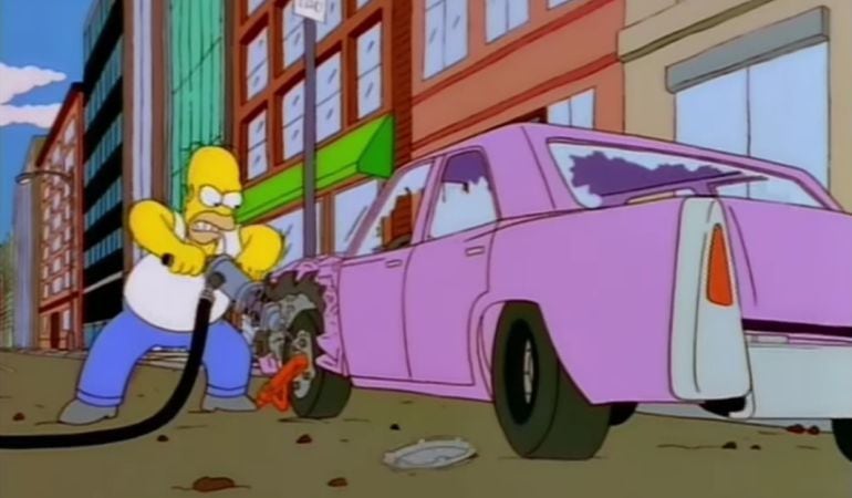 Homer Simpson tratando de quitar un cepo de su vehículo.