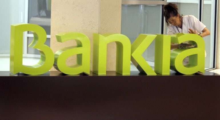 Una operaria limpia el logo de Bankia en la sede central de Bancaja