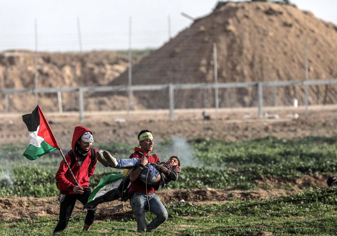 Dos jóvenes palestinos llevan en brazos a un niño herido durante las protestas de los viernes contra Israel en la ciudad cisjordana de Gaza.