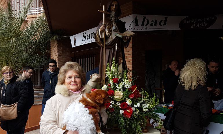 Una mujer y su perro posan junto al santo