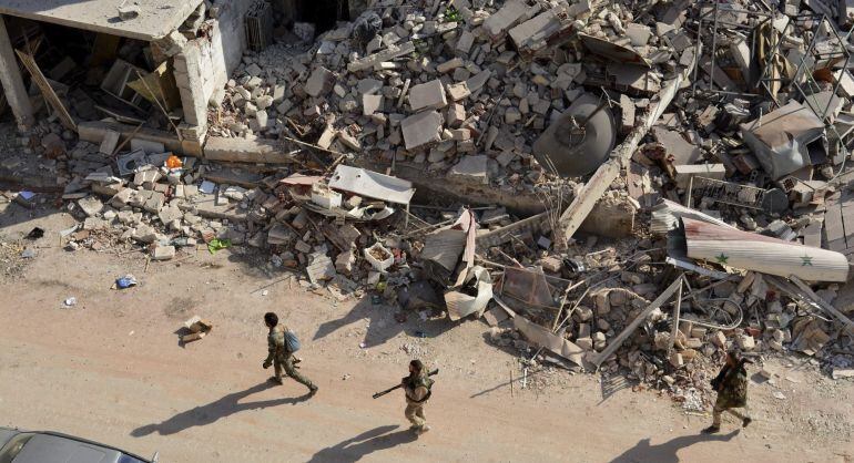 Soldados sirios caminan entre los escombros en el oeste de Alepo tras los bombardeos.