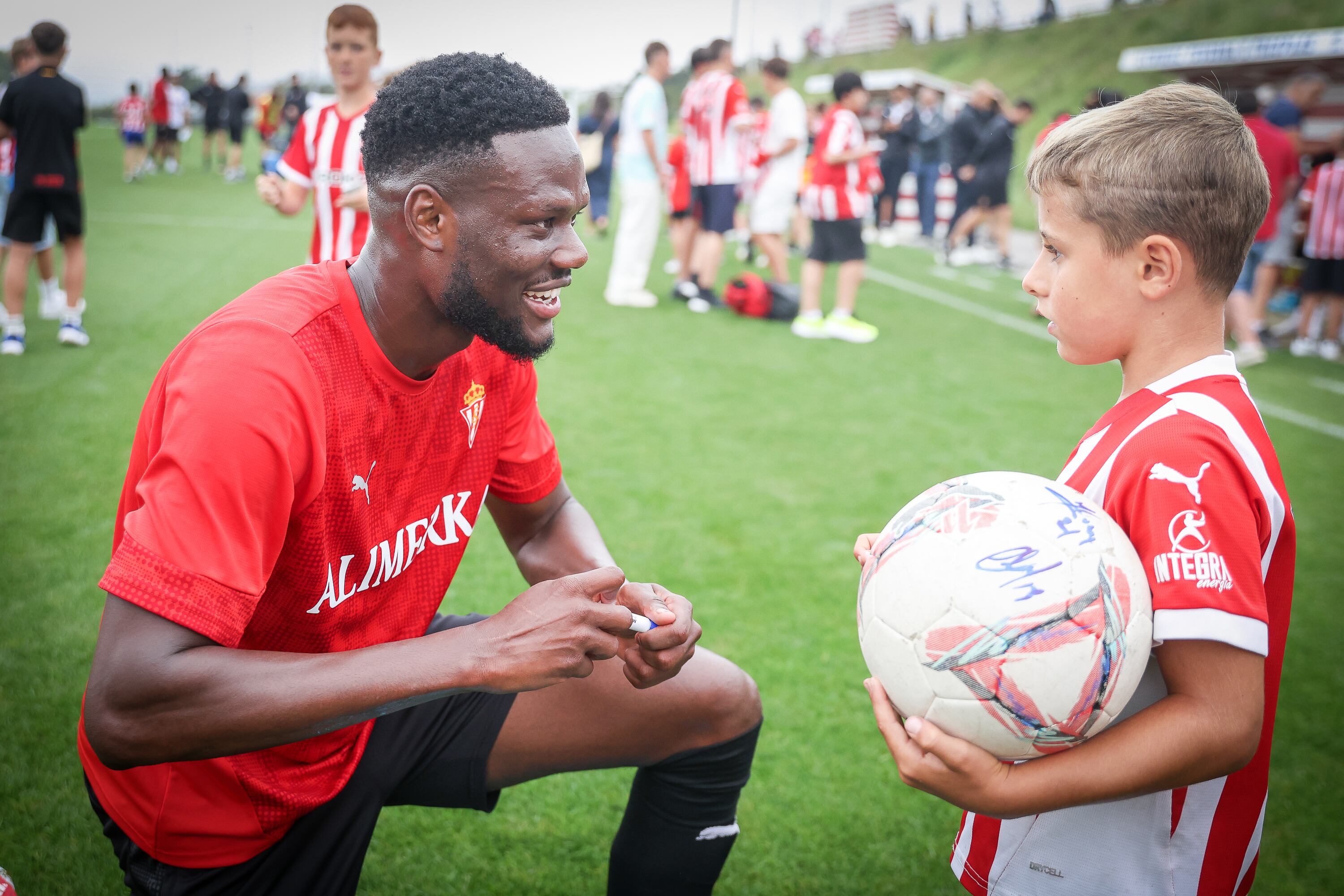 Mamadou Loum charla con un niño tras su primer entrenamiento como jugador del Sporting.