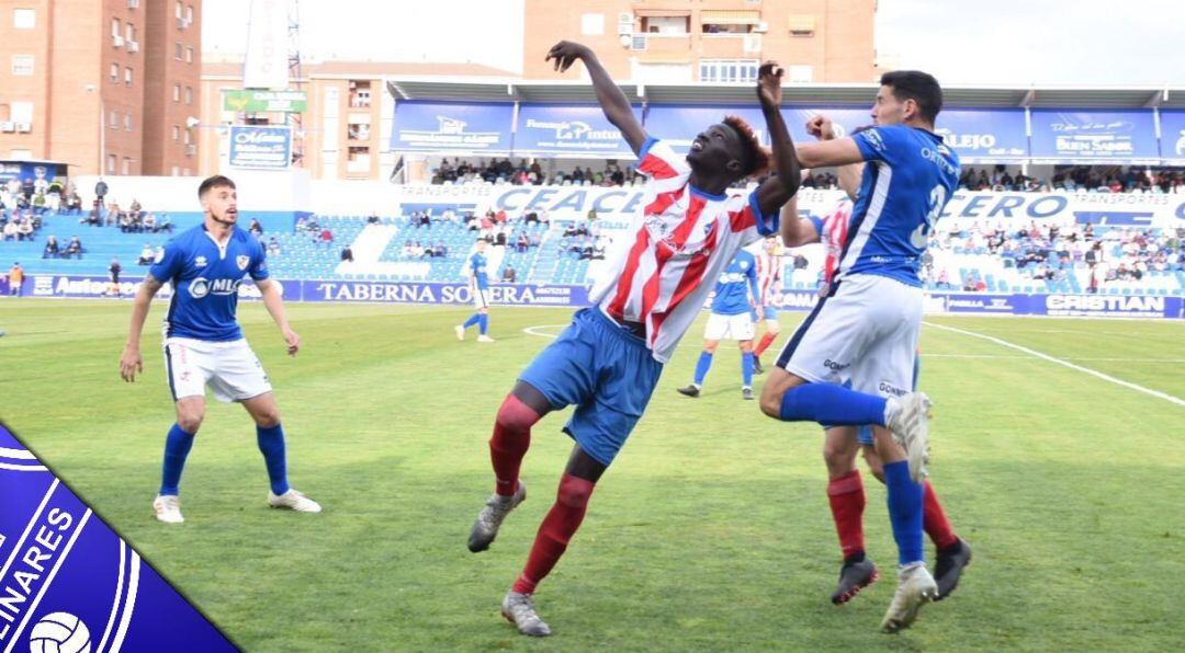 Espejo, jugador del Linares Deportivo, pugna por un balón con un futbolista del equipo contrario.