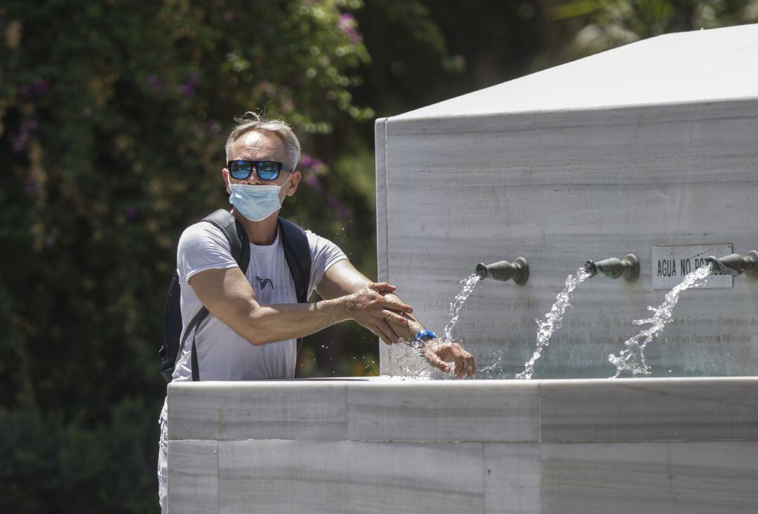 Un hombre se refresca en una fuente.