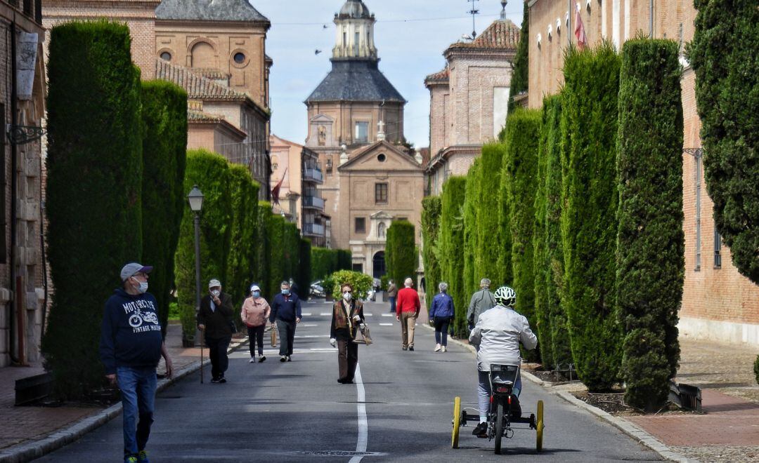 Vecinos de Alcalá de Henares andando por la calzada de la calle Colegios