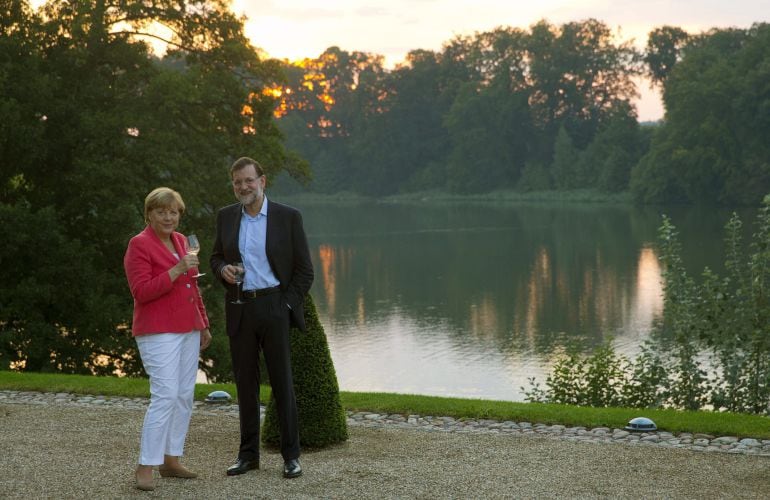 El presidente del gobierno español, Mariano Rajoy y la cancillera alemana Angela Merkel por el entorno del lago de Schloss en el castillo de Meseberg (Alemanía).