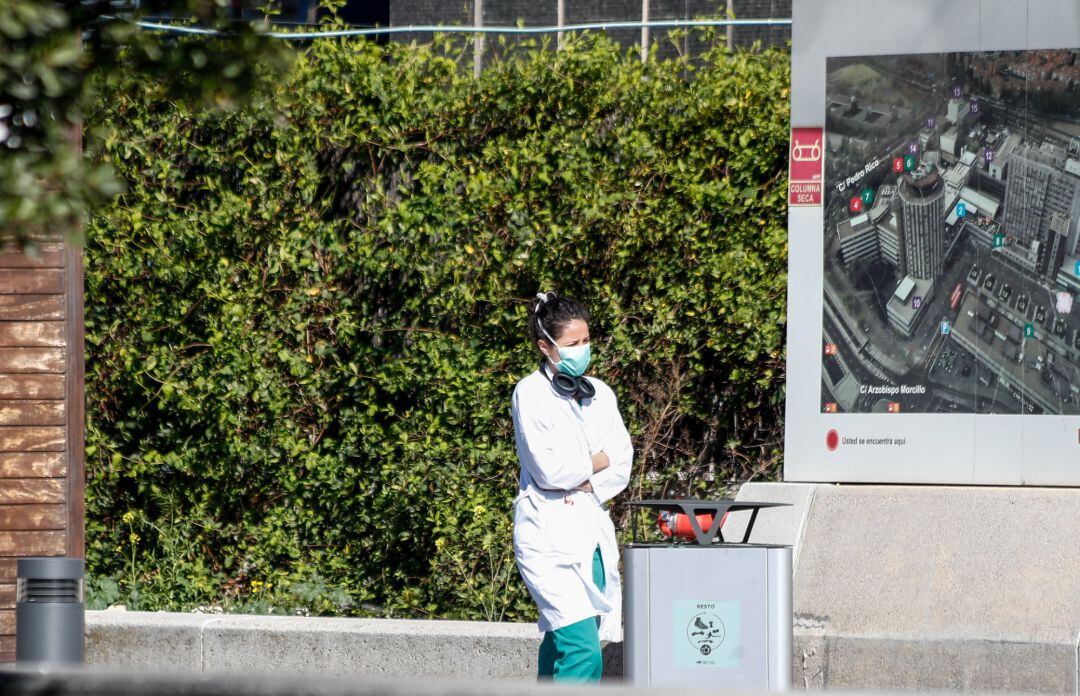 Una sanitaria protegida con mascarilla descansa en las inmediaciones del Hospital La Paz.