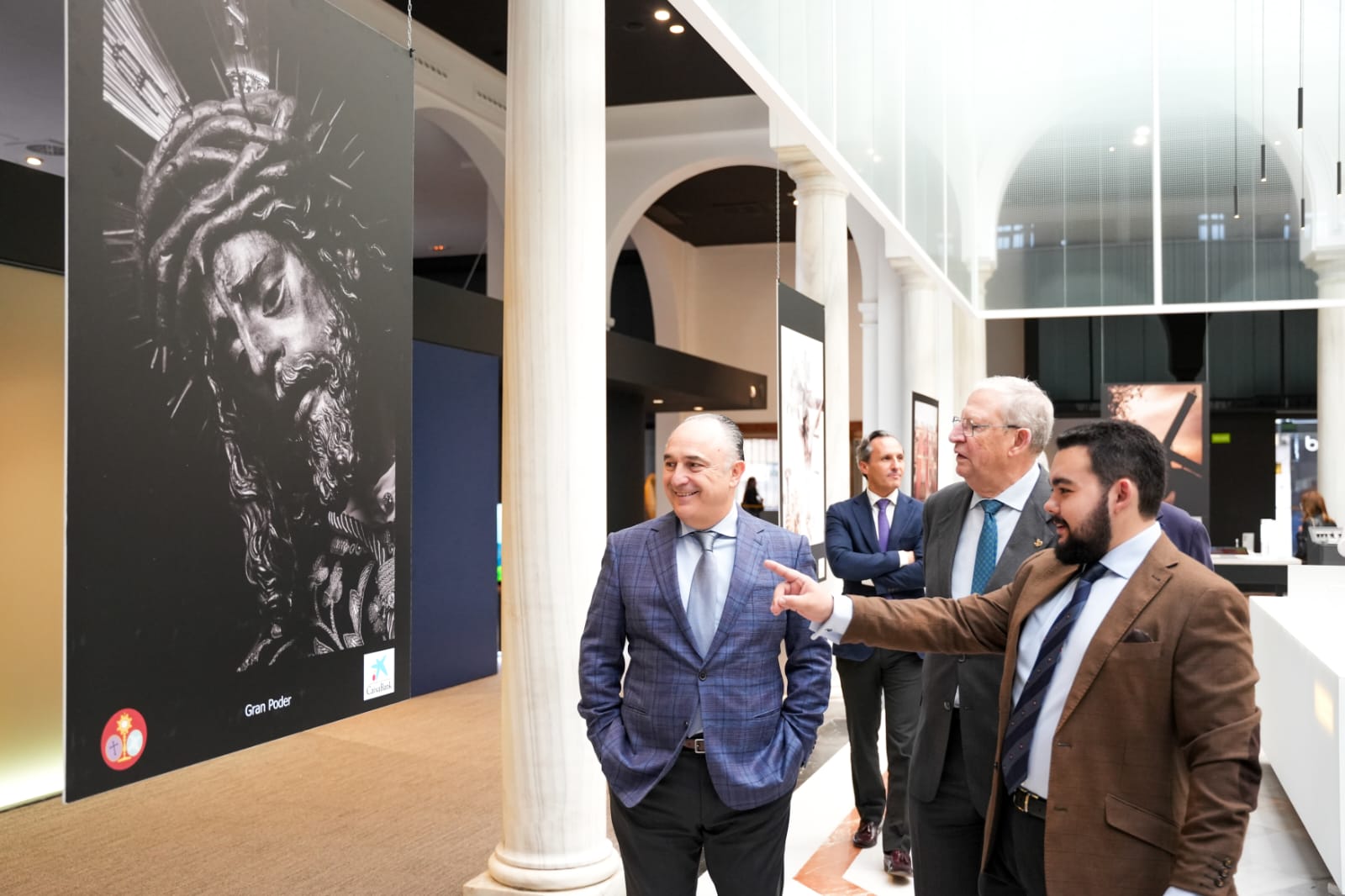 Alejandro del Castillo muestra una fotografía del Gran Poder al director territorial de CaixaBank en Andalucía, Juan Ignacio Zafra, y al presidente del Consejo de Hermandades, Francisco Vélez de Luna